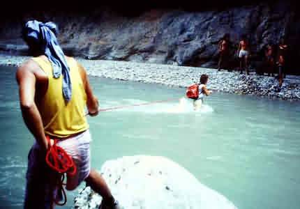 Canyoning: hiking down a river. Crossing the river with a rope